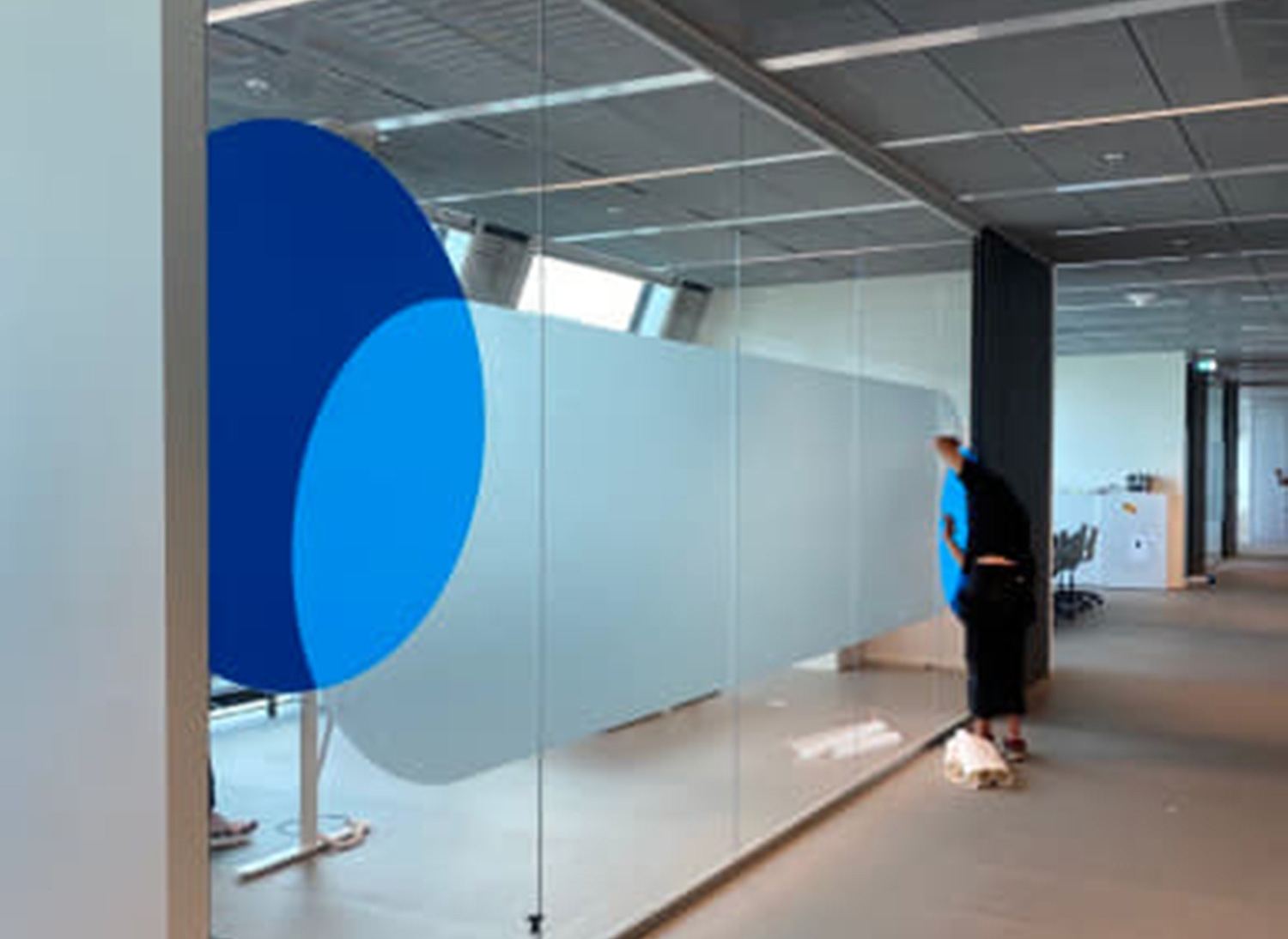 Montage einer Dekorfolie mit blauen Kreisen auf einer Büro-Glaswand